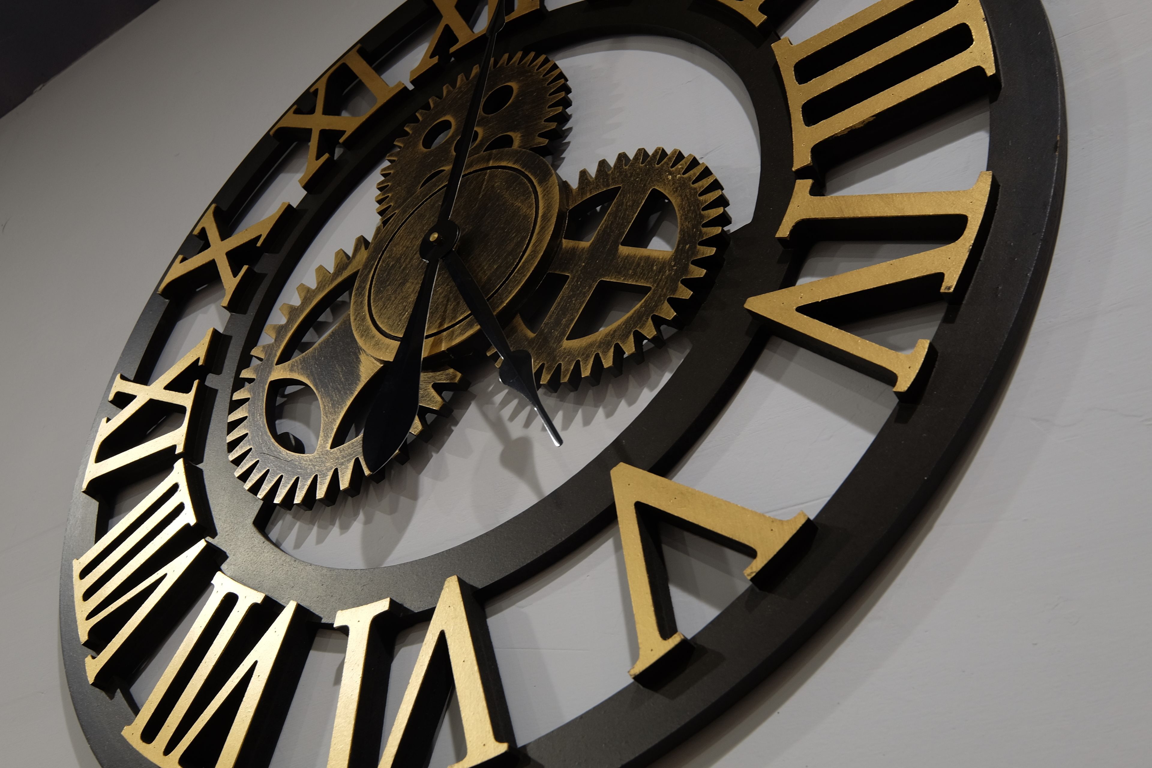 A large wall clock with Roman numerals and mechanical gears.