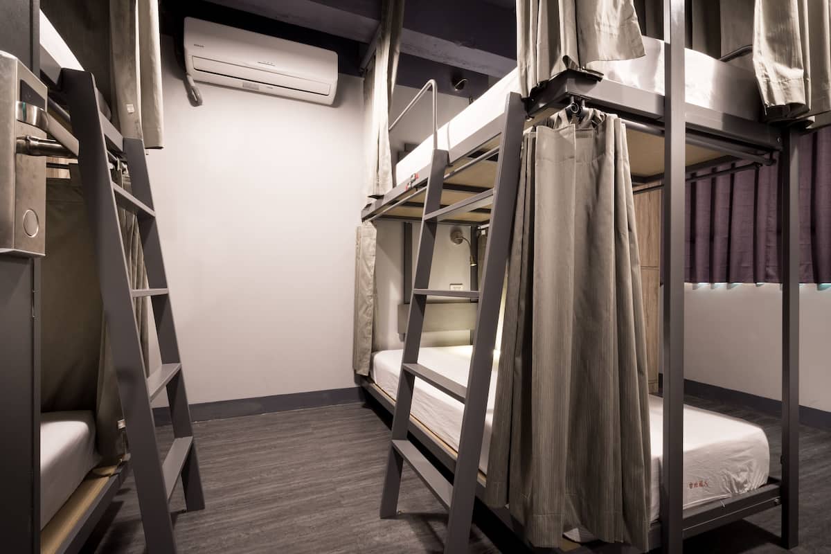 A bunk bed room with a ladder, a bed, and a curtain.