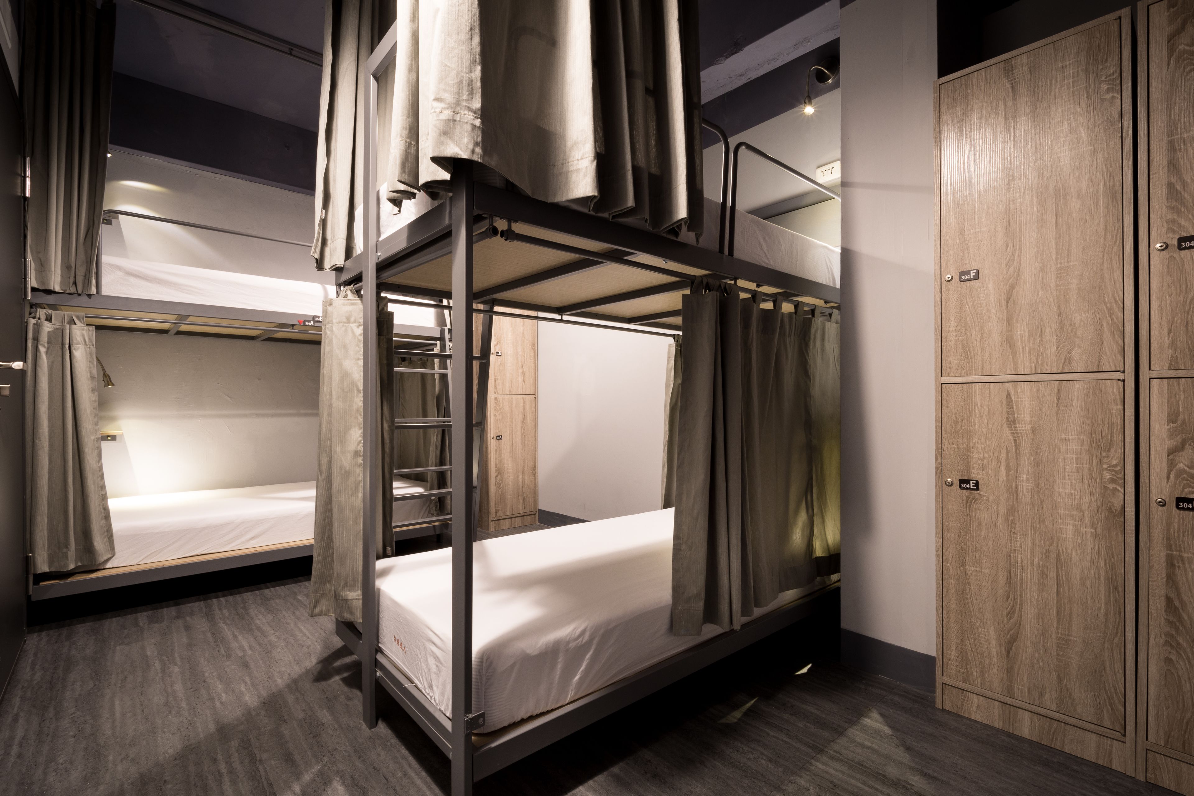 A bunk bed room with a wooden wardrobe and a metal ladder.