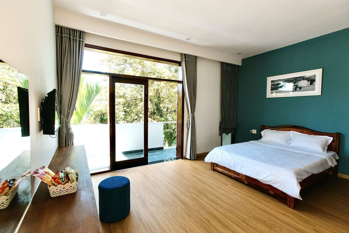 Une chambre avec un lit, un bureau en bois, un panier de collations et une vue sur l’extérieur grâce à une porte coulissante.