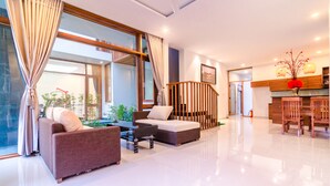A modern living room with a sofa, a coffee table, and a staircase leading to another level. - Green World Hoi An Villa (Da Nang)