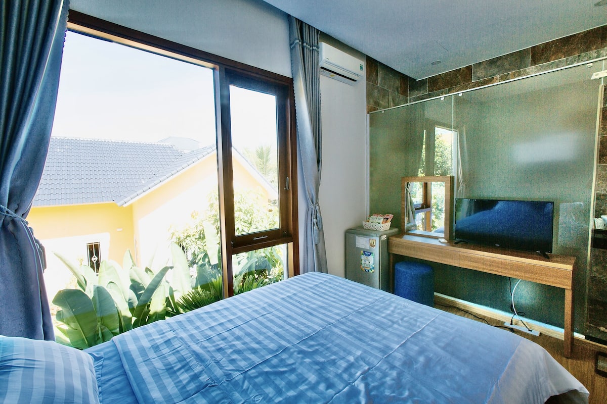 Une chambre d’hôtel avec un lit, une télévision, un bureau et une fenêtre avec des rideaux.