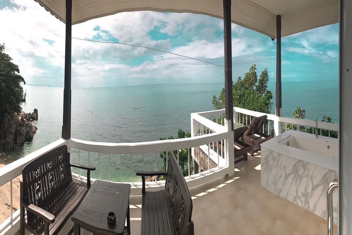 En balkon med havudsigt, et siddeområde med bord og stole samt et marmorbadekar.