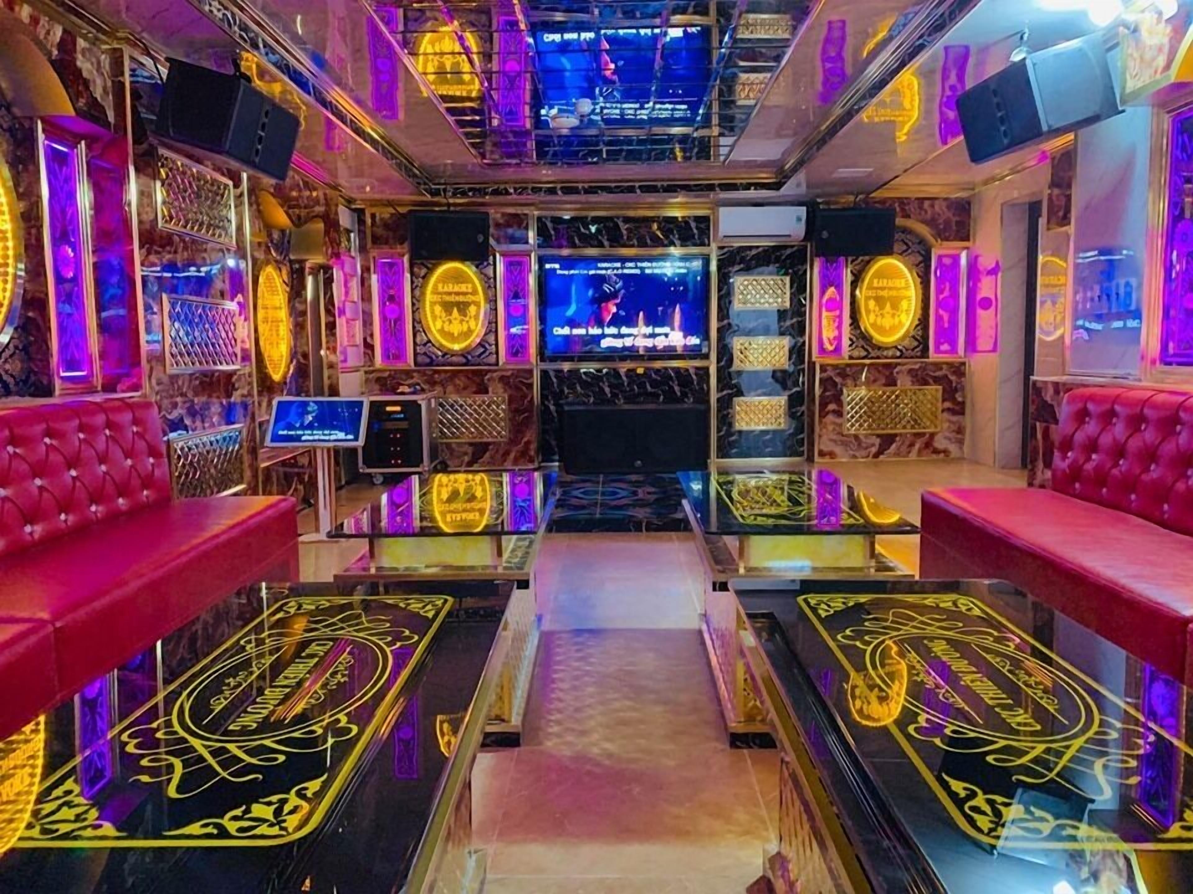 Zona de bar con asientos tapizados en rojo, una barra central y letreros de neón.
