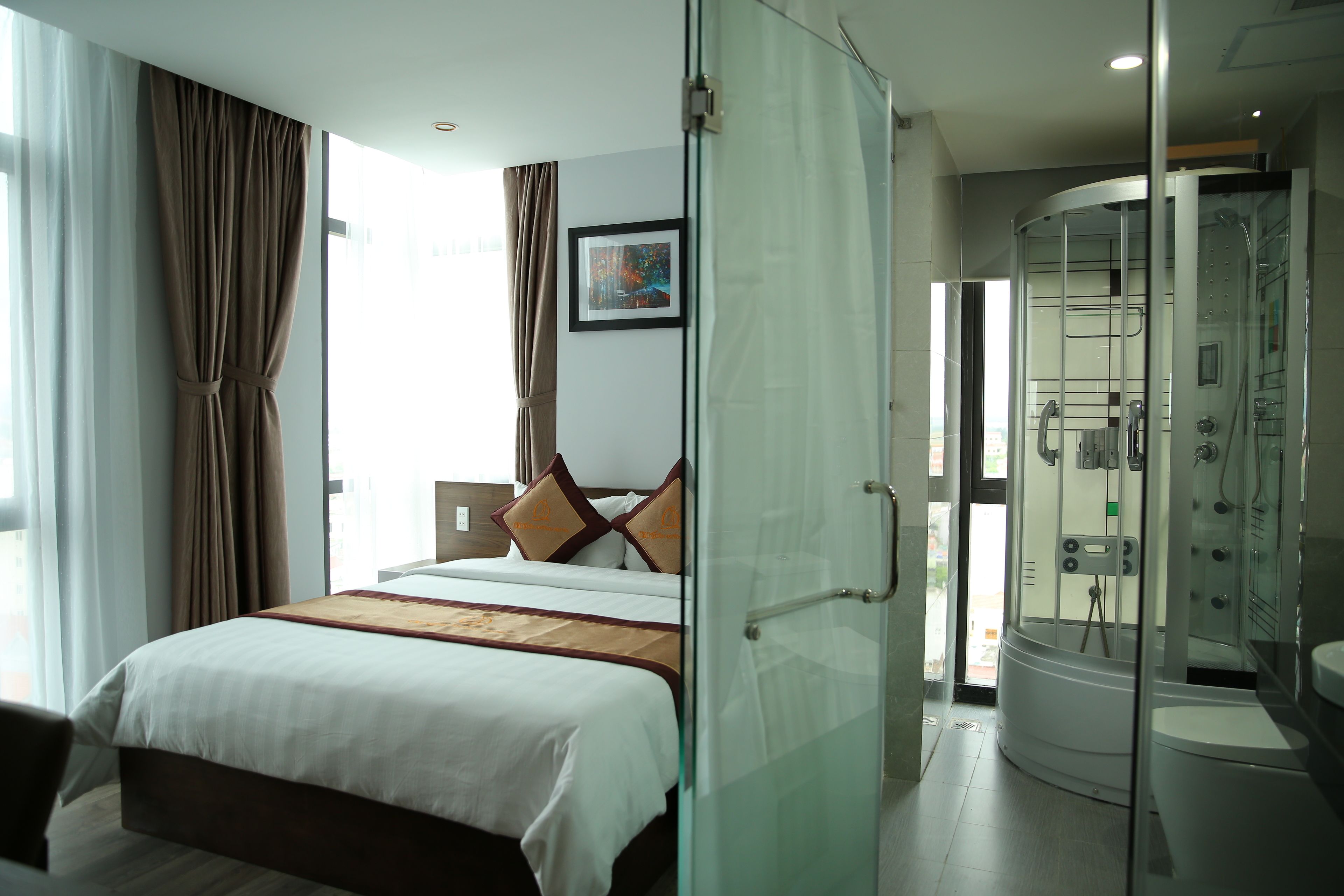 Una habitación de hotel moderna con una cama grande, ducha con cerramiento de vidrio y vistas al exterior.