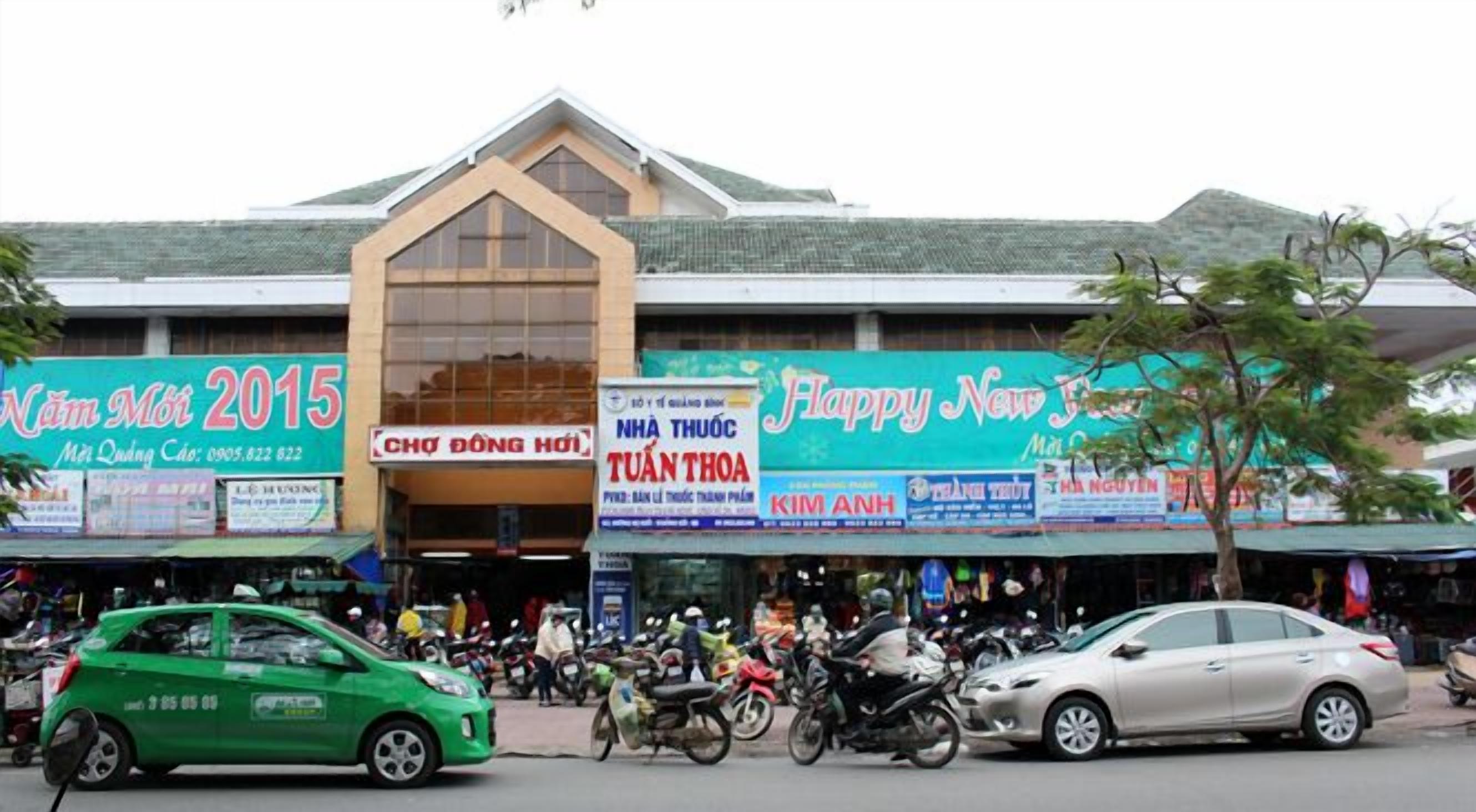 Un edificio con varias fachadas, incluyendo carteles que dicen 'Năm Mới 2015' y 'Feliz Año Nuevo'.