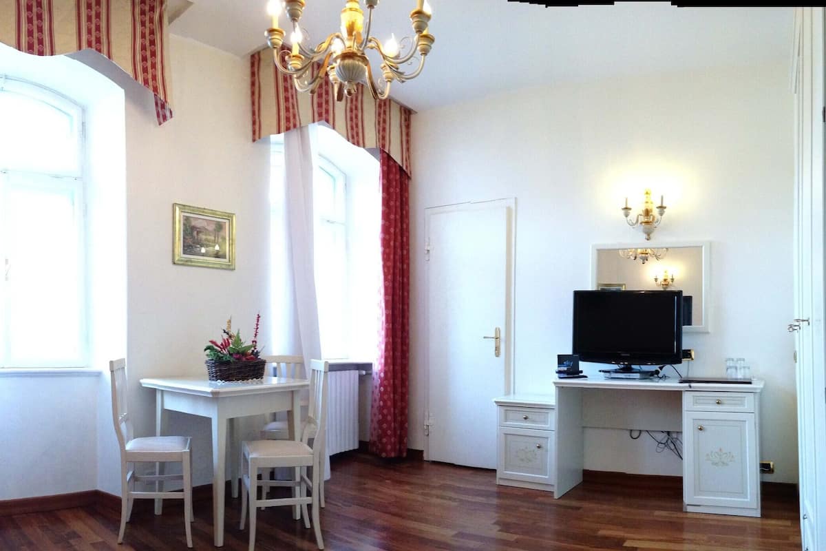 Ein Zimmer mit einem roten Sofa, einem Esstisch mit Stühlen, einem Fernseher und einem kleinen Schrank.