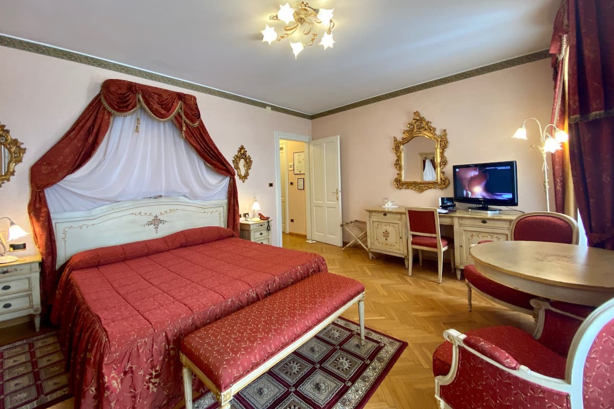 Ein Schlafzimmer mit einem großen Bett, einem Schreibtisch mit Stuhl, einem Fernseher und einem Spiegel an der Wand.