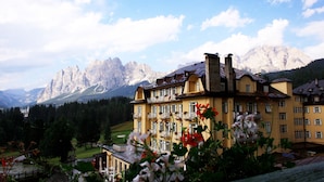 Ein großes Hotel mit mehreren Balkonen und einer Bergkulisse.