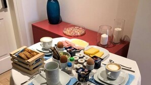 Una mesa de desayuno preparada con platos, tazas, cubiertos y una variedad de alimentos.