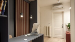 Un mostrador de recepción con una computadora, una pared a rayas, un radiador y una puerta.