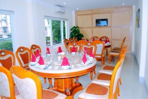 Un comedor con una mesa redonda dispuesta para una comida, rodeada de sillas naranja y blancas.