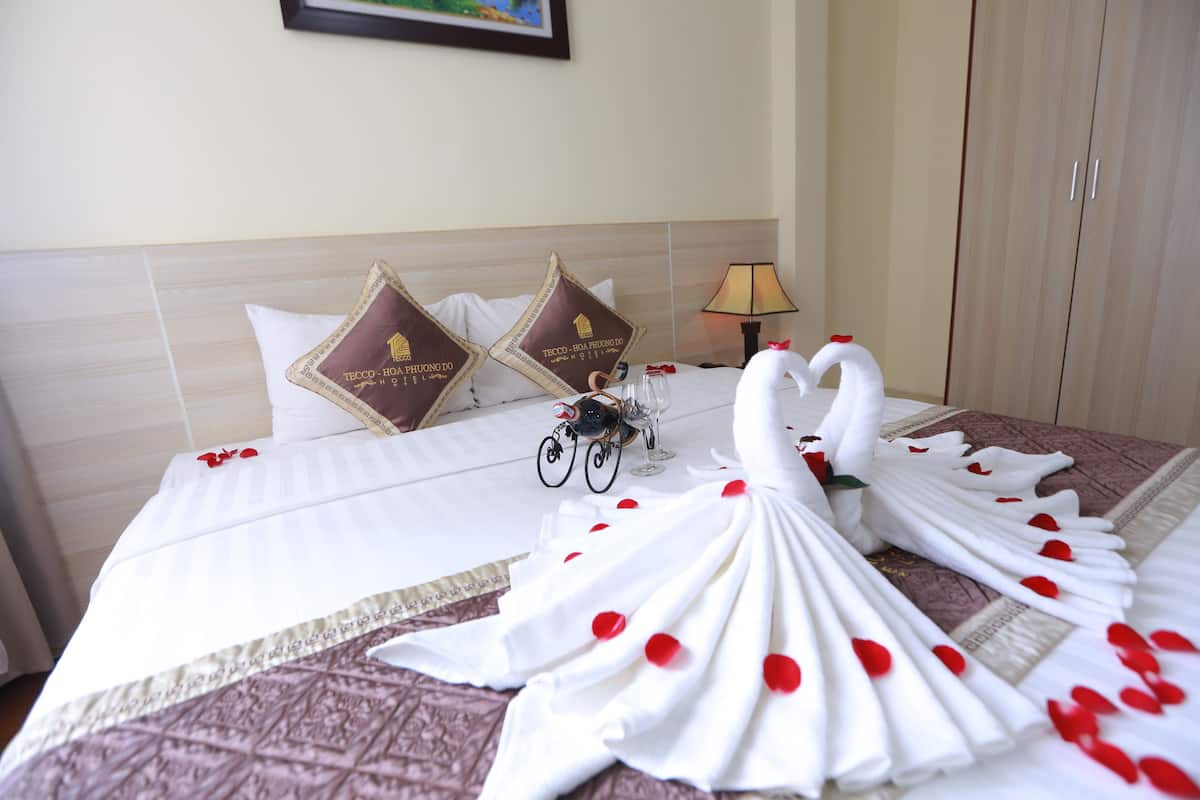A neatly made bed with white linens, two decorative pillows, a small bicycle decoration, and a swan towel arrangement.