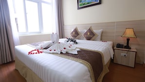 A hotel room with a large bed, a nightstand with a lamp, and a painting on the wall. - Tecco Sky Hotel (Thanh Vinh)