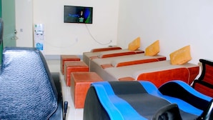 A conference room with rows of chairs, a television mounted on the wall, and a water dispenser. - Tecco Sky Hotel (Thanh Vinh)