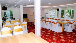 A conference room with a large table and chairs, red patterned carpet, and large windows with greenery outside. - Tecco Sky Hotel (Thanh Vinh)