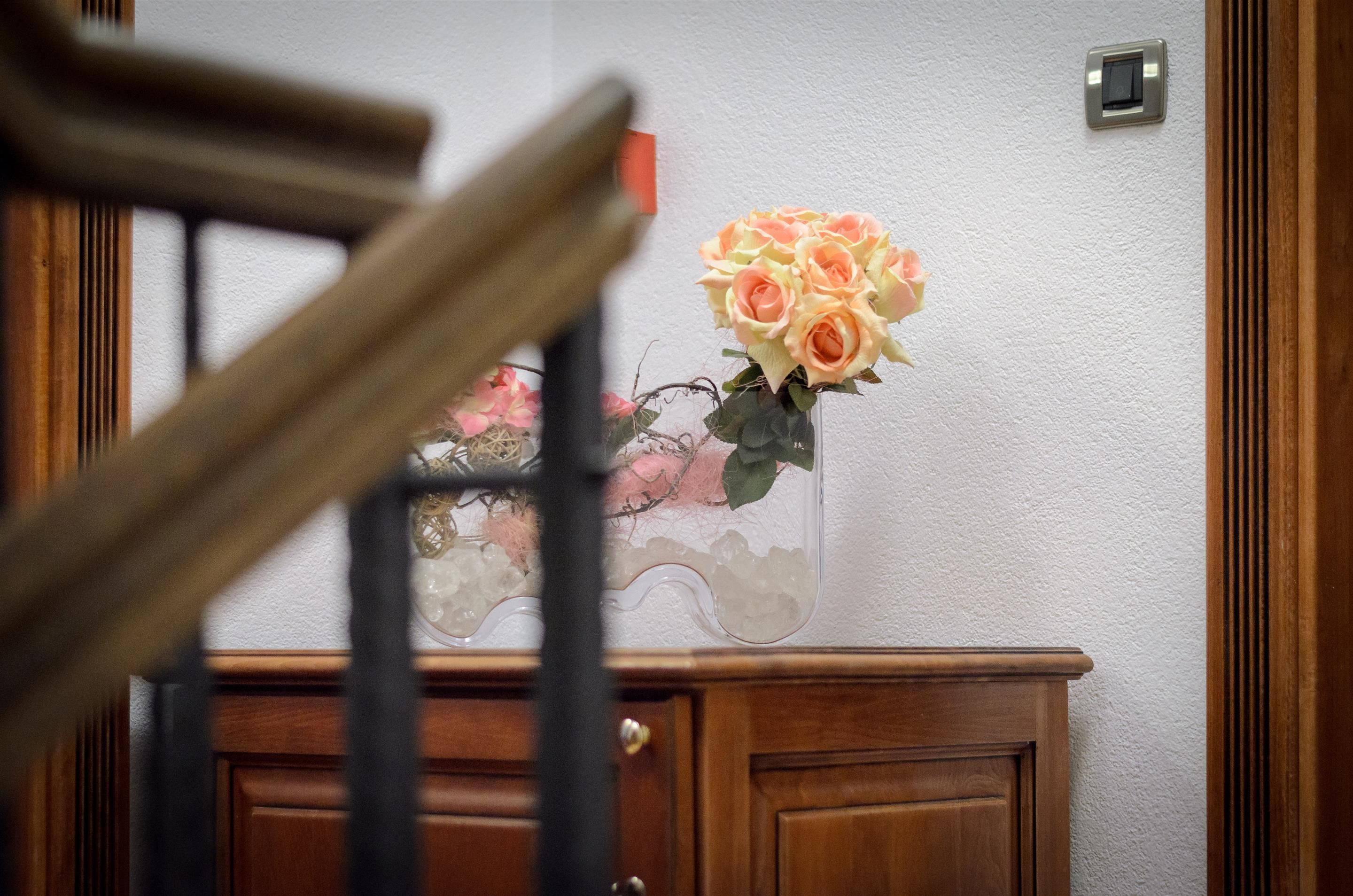A wooden cabinet with a vase of flowers on top.