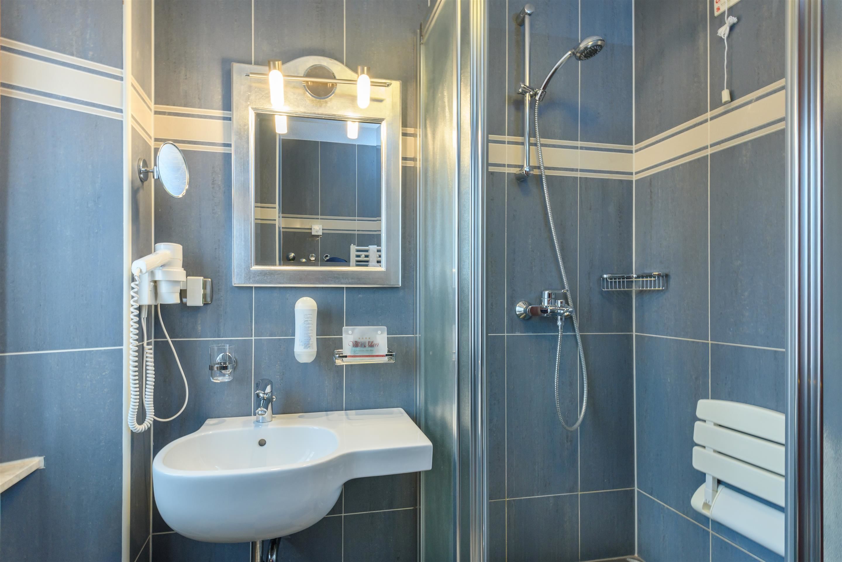 Un baño con lavamanos, espejo y ducha.