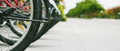 A close-up of a bicycle wheel with a rack attached, parked on a paved surface.