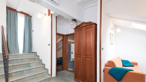 A staircase leading to a landing with a wooden wardrobe and a sofa with a blue throw. - Villa Meri (Trogir)