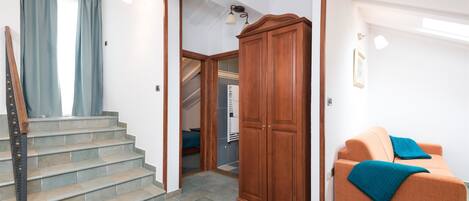 A staircase leading to a landing with a wooden wardrobe and a sofa with a blue throw.