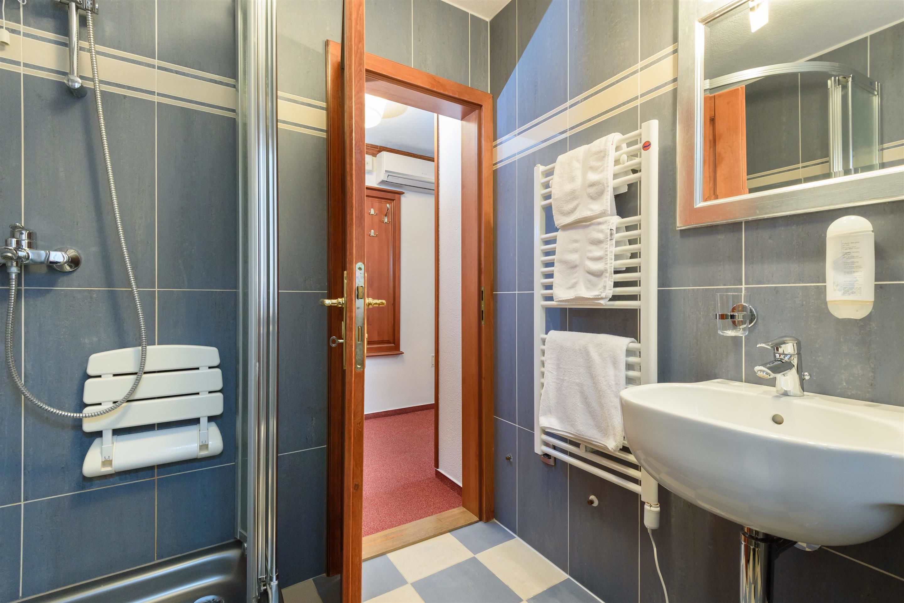 A bathroom with a shower, a sink, and a mirror.