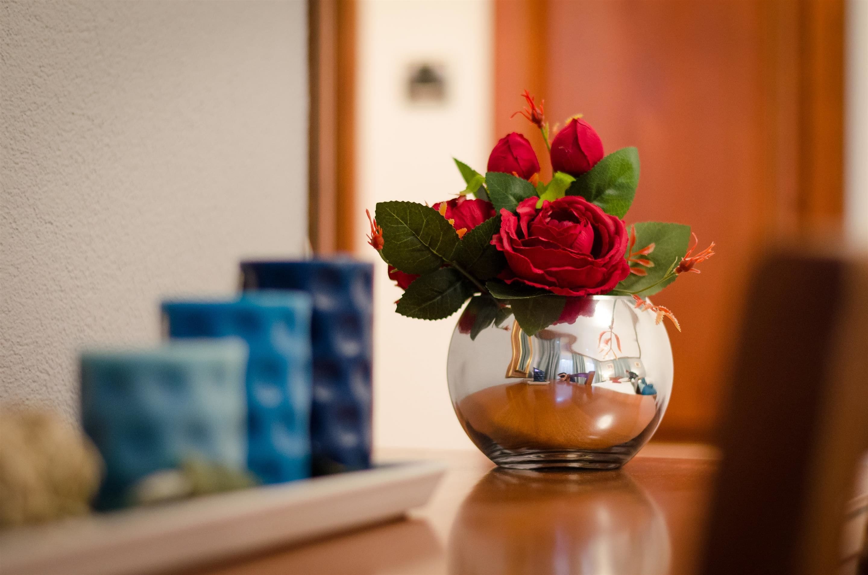 Un florero de vidrio transparente con rosas rojas sobre una mesa de madera.