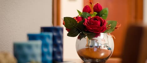 A clear glass vase with red roses on a wooden table.