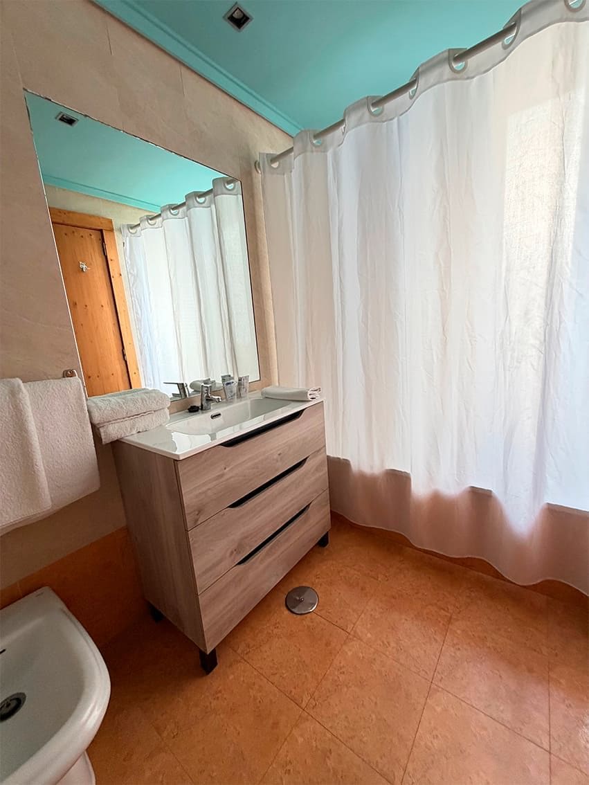 Un baño con lavamanos, espejo e inodoro.