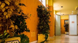 Un pasillo de hotel con paredes de madera, suelo de baldosas y plantas en macetas.