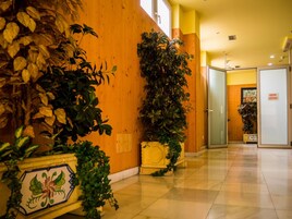 Un pasillo de hotel con paredes de madera, suelo de baldosas y plantas en macetas.