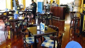 Un restaurante con mesas y sillas de madera, una zona de bar y una cocina al fondo.