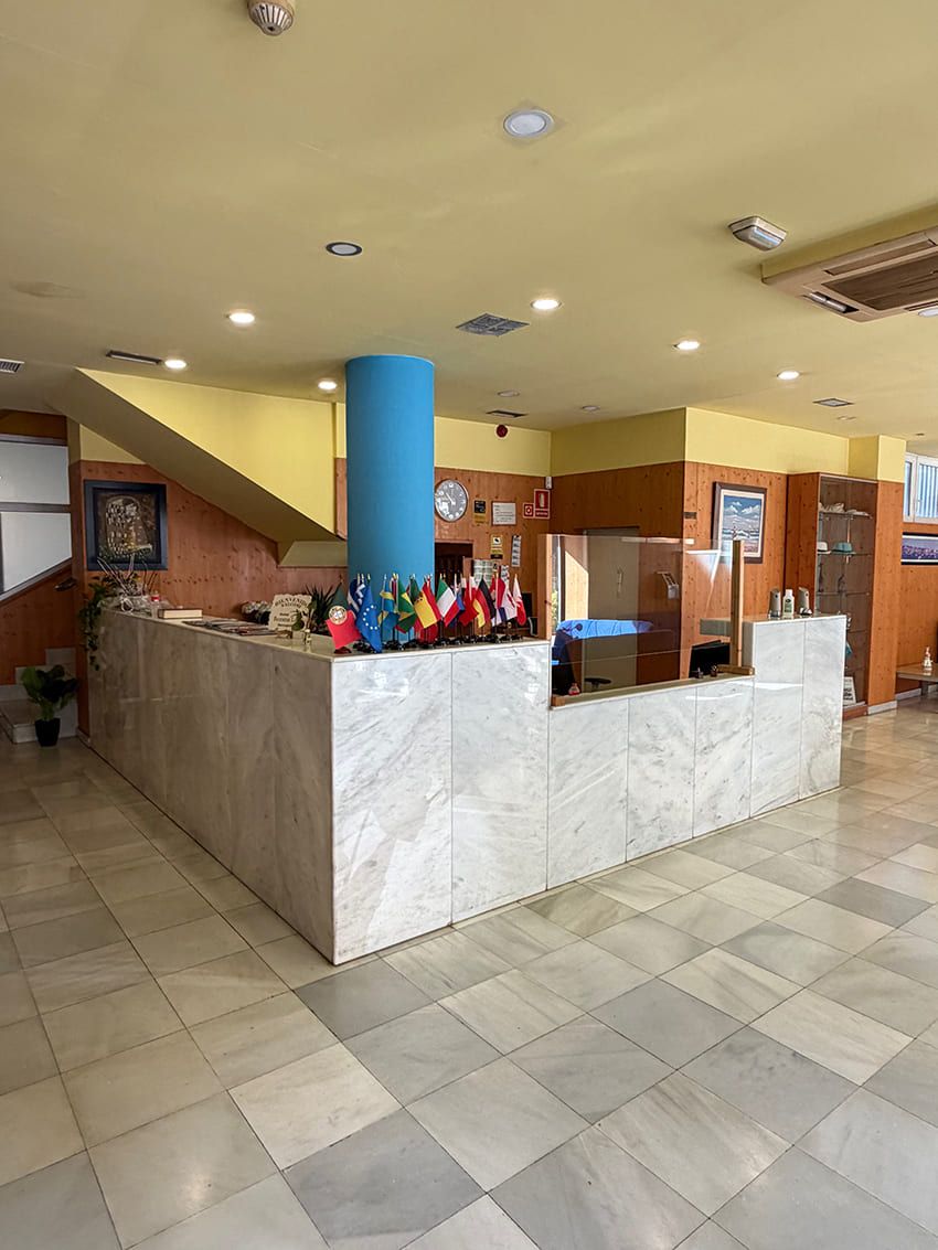A reception desk with a marble counter, a blue pillar, and flags.