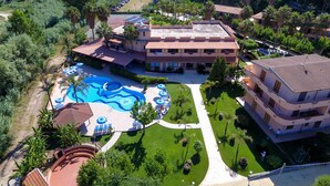 An aerial view of a resort with a swimming pool, multiple buildings, and lush greenery. - Old River Residence (Ricadi)
