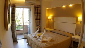A hotel room with a large bed, a bedside table with a lamp, and a view of the outdoors through a sliding door. - Old River Residence (Ricadi)
