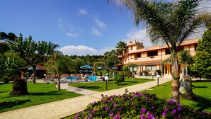 A resort with a swimming pool, palm trees, and a well-maintained lawn. - Old River Residence (Ricadi)