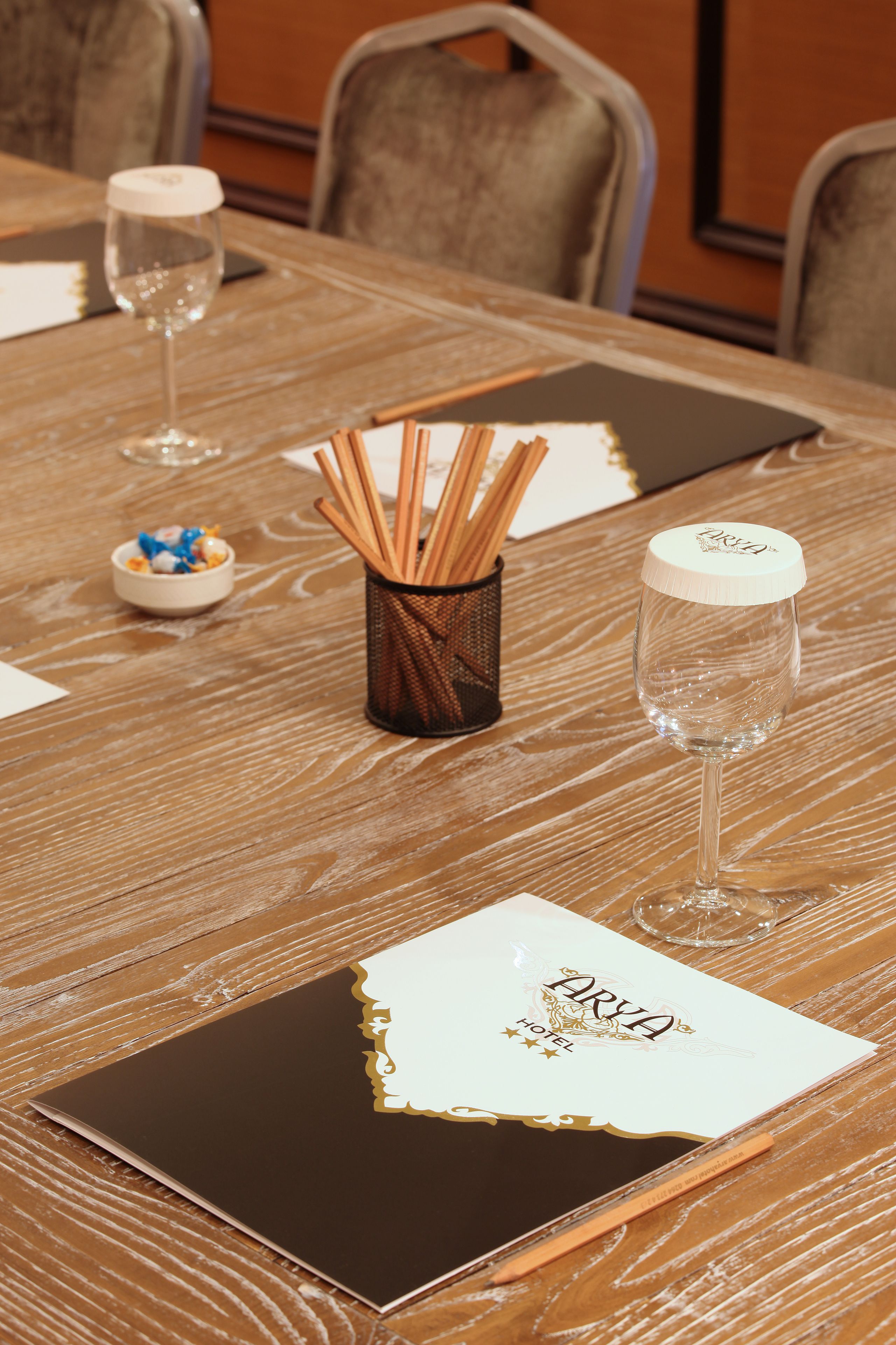 A wooden table with a name card, a glass, and a container of utensils.