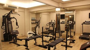 Een fitnessruimte met diverse trainingsapparaten, waaronder loopbanden en gewichtstoestellen, en een spiegelwand.