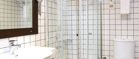 A modern bathroom with a glass-enclosed shower, white sink, and toilet.
