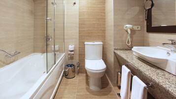 A modern bathroom with a glass-enclosed shower, a toilet, and a sink with a mirror above it.