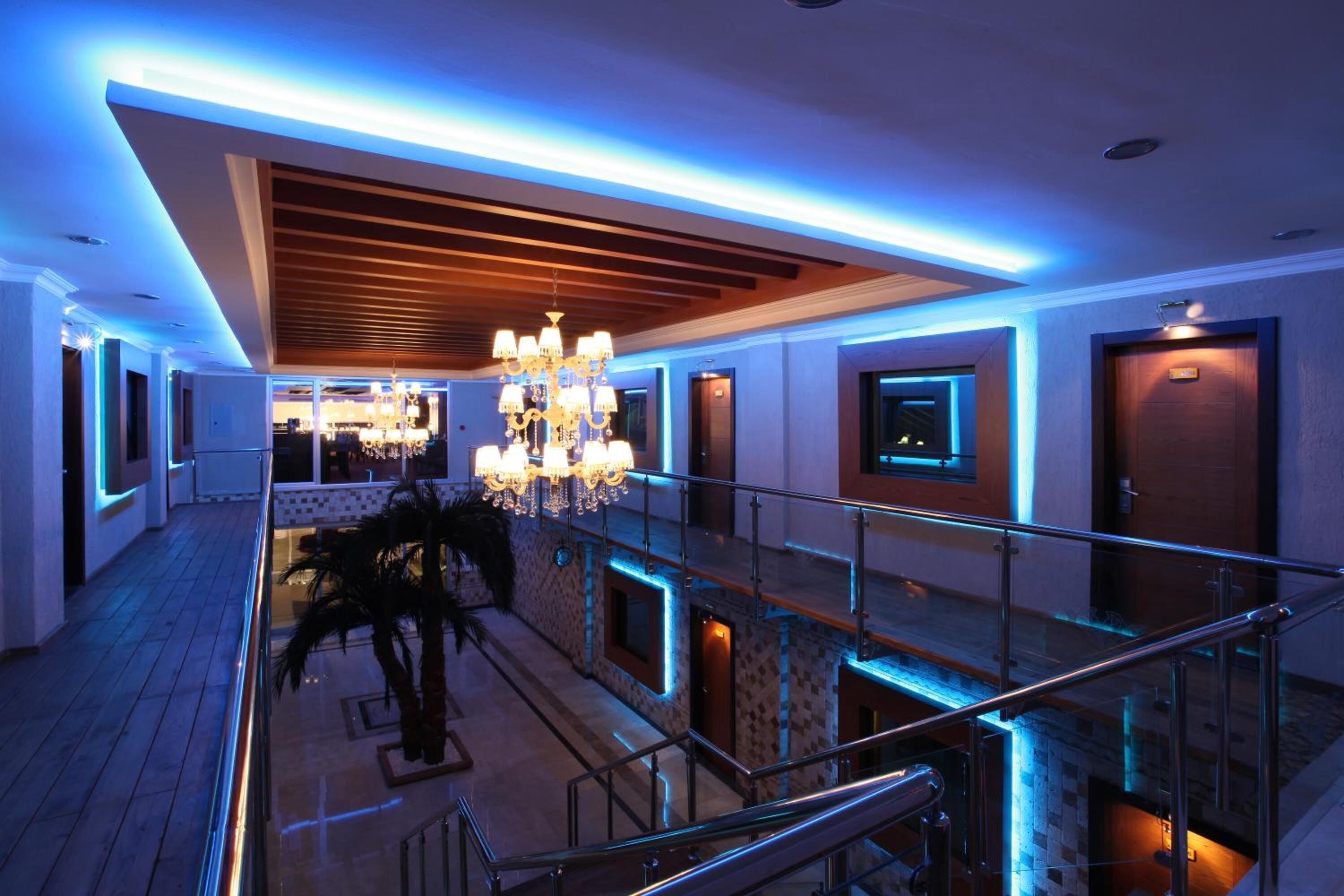 A modern hotel lobby with a wooden ceiling, a chandelier, and a glass railing.