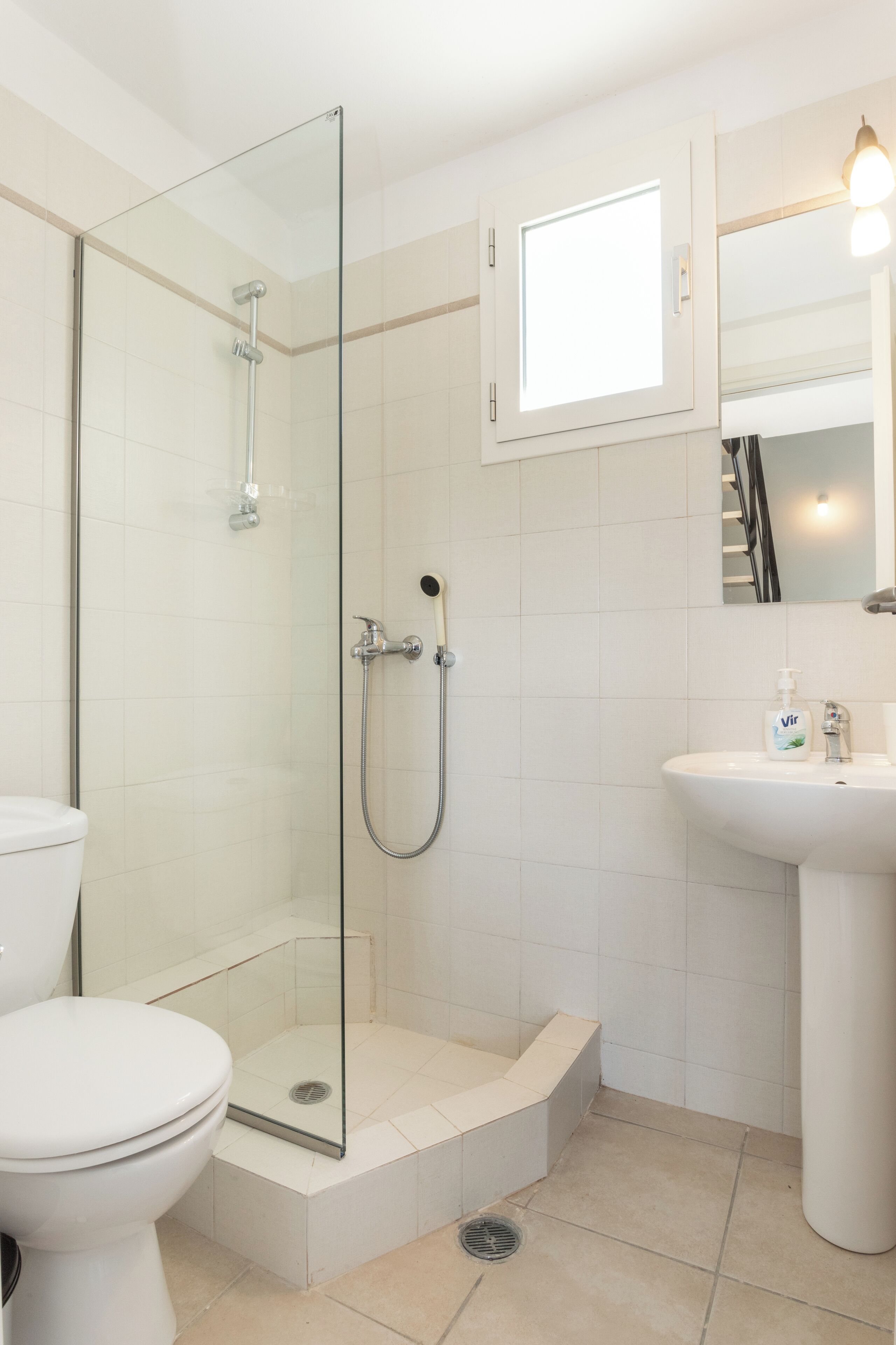 Een moderne badkamer met een douchecabine van glas, een wit toilet en een wastafel met spiegel.