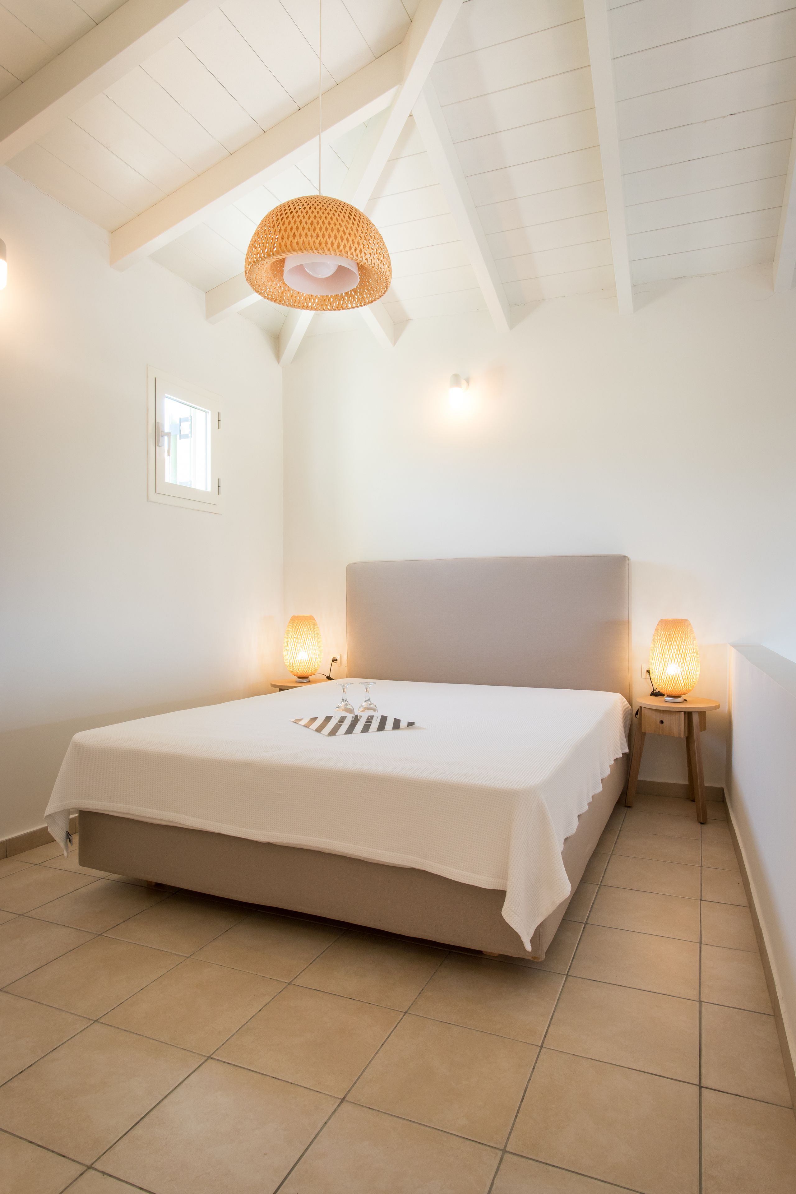 Quarto com uma cama grande, duas luminárias de cabeceira e um lustre.