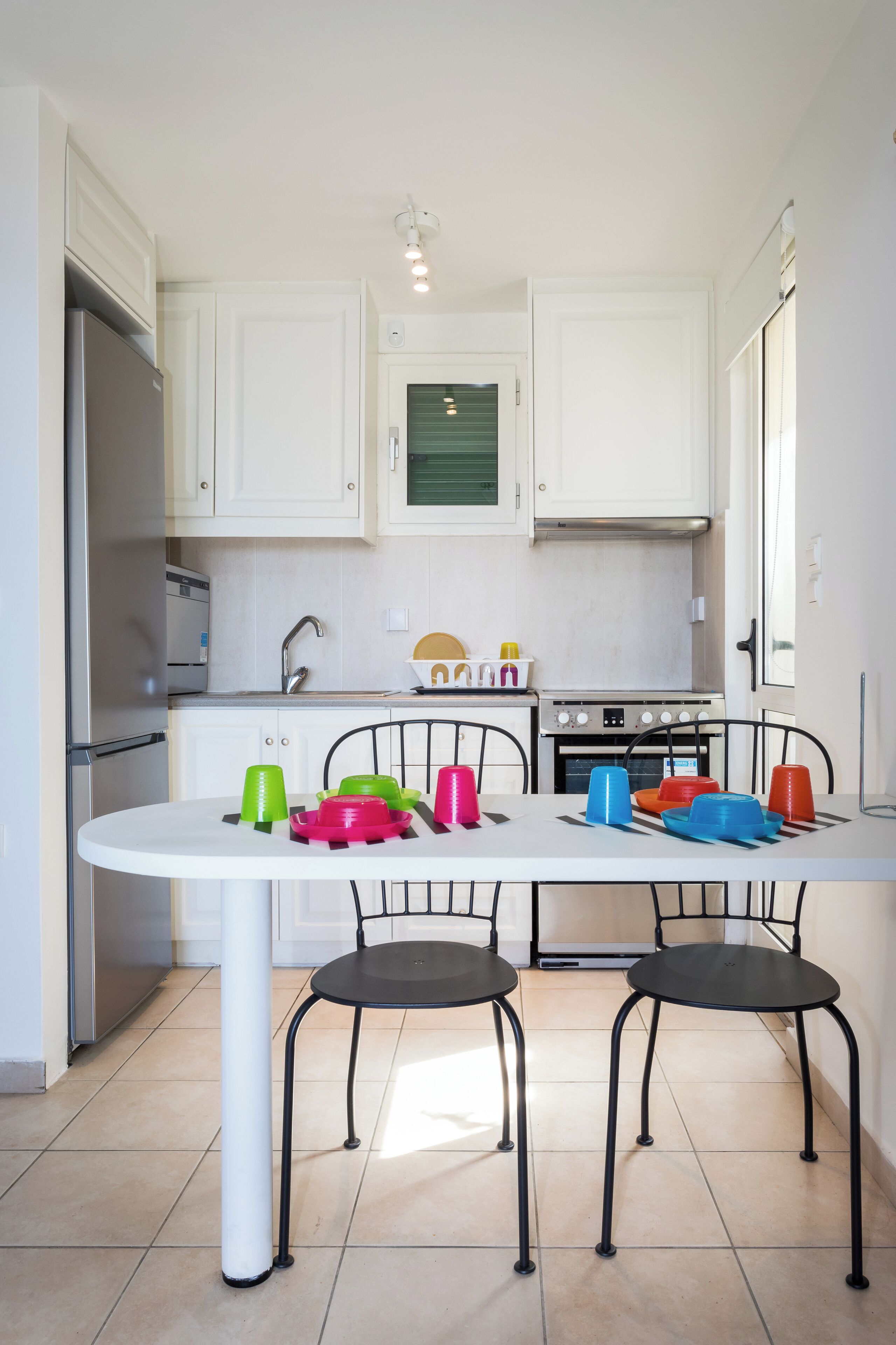 Une cuisine avec des meubles blancs, une cuisinière et une table à manger avec des chaises.