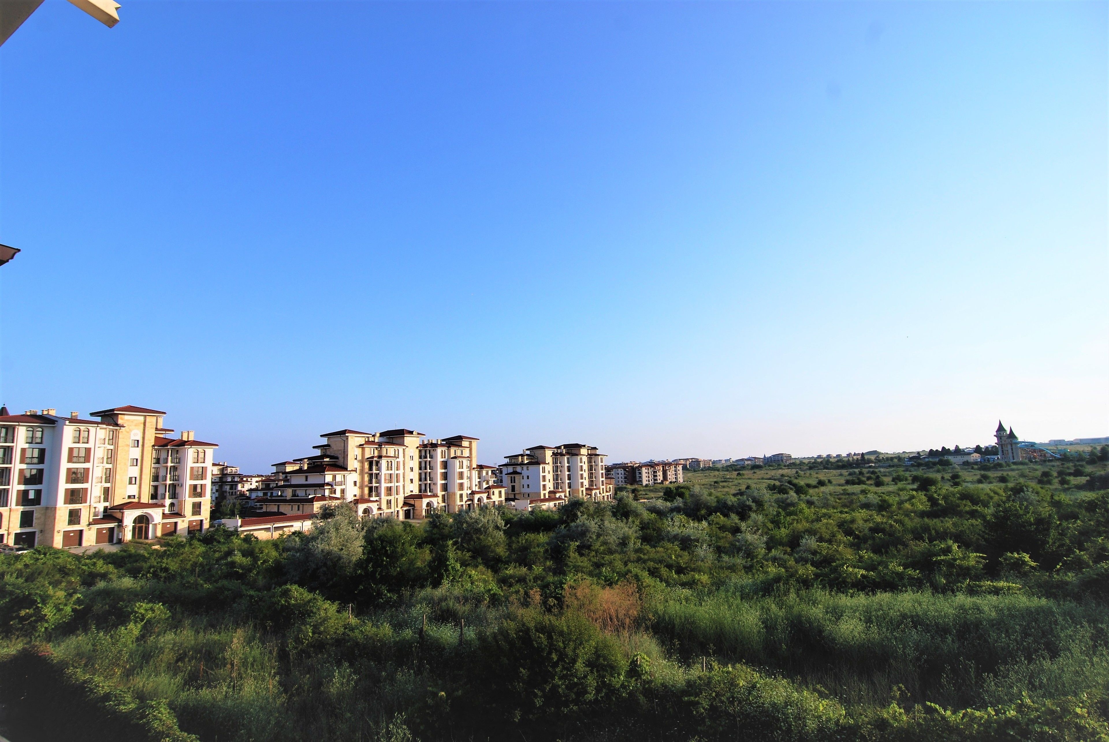 A residential area with multi-story buildings and a church in the distance.