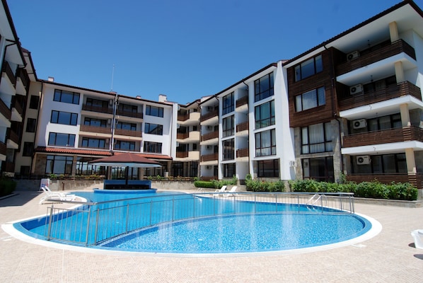 A swimming pool surrounded by multi-story buildings with balconies and air conditioning units.