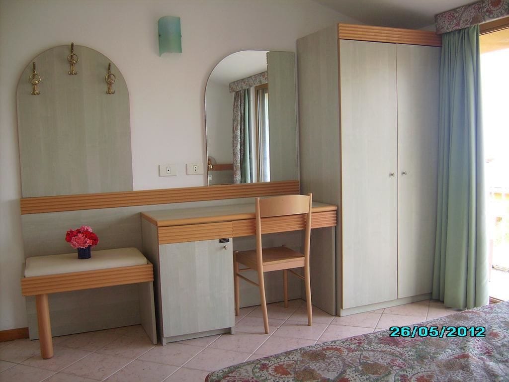 Quarto com escrivaninha, cadeira, guarda-roupa e espelho.