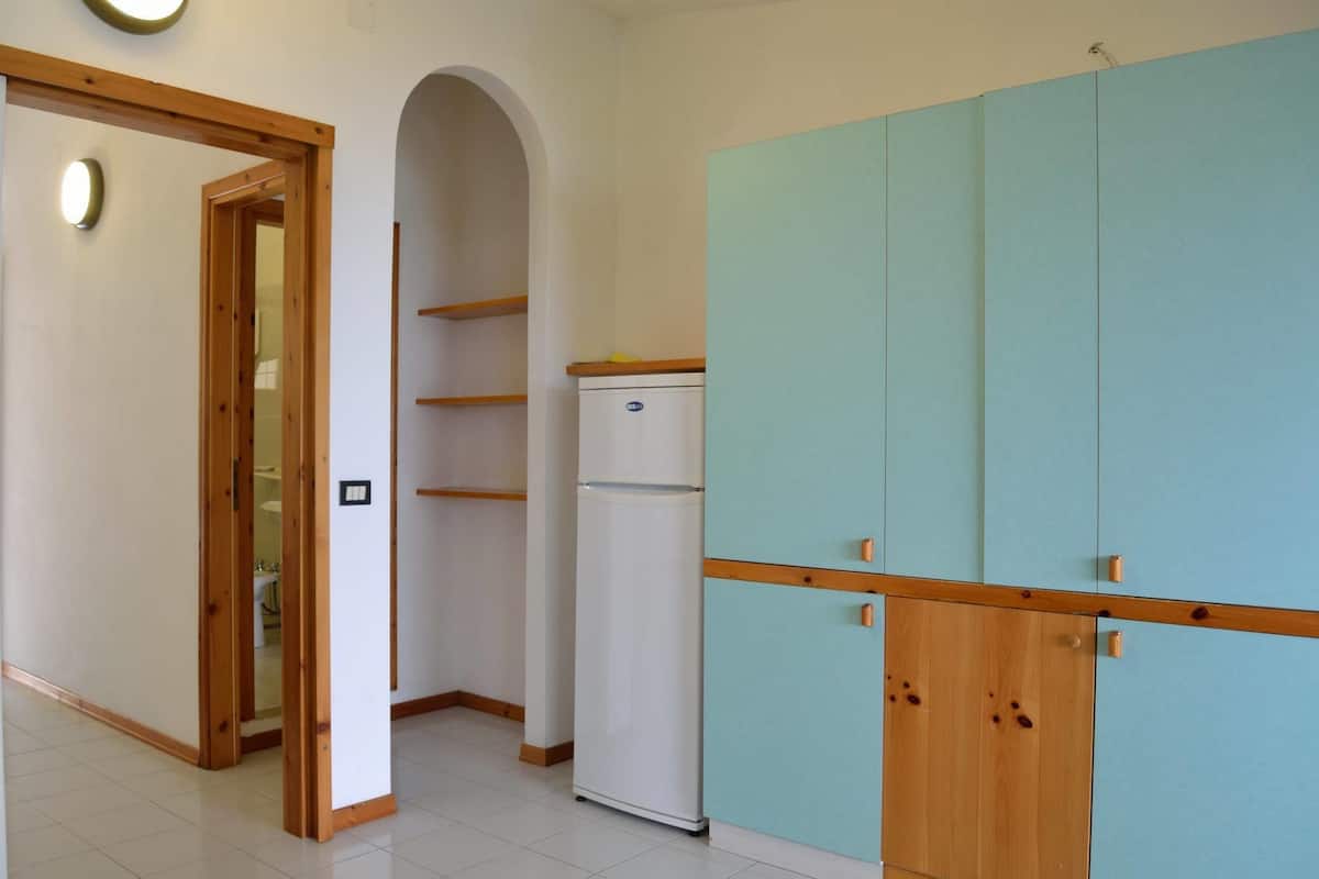Une pièce avec une porte en bois, un réfrigérateur blanc et une armoire bleue.