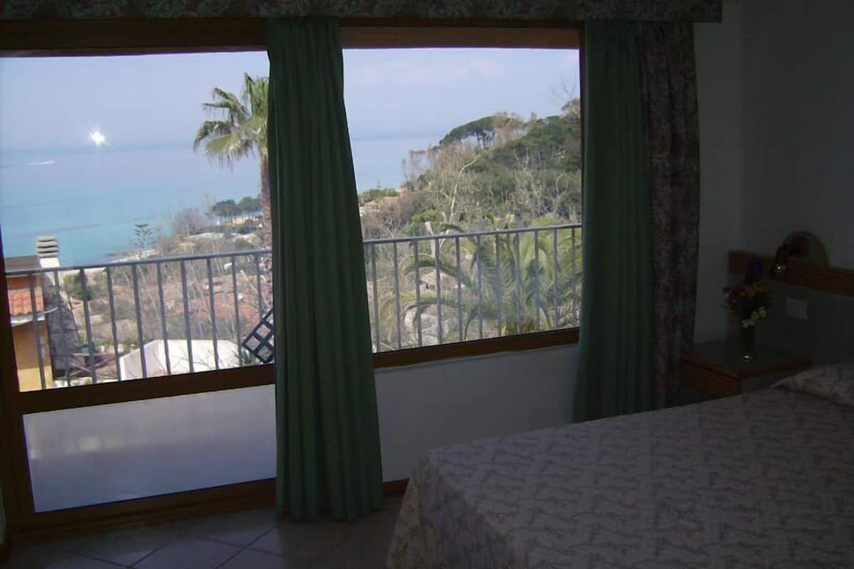 Une chambre avec un grand balcon, un lit et une vue sur l’océan.