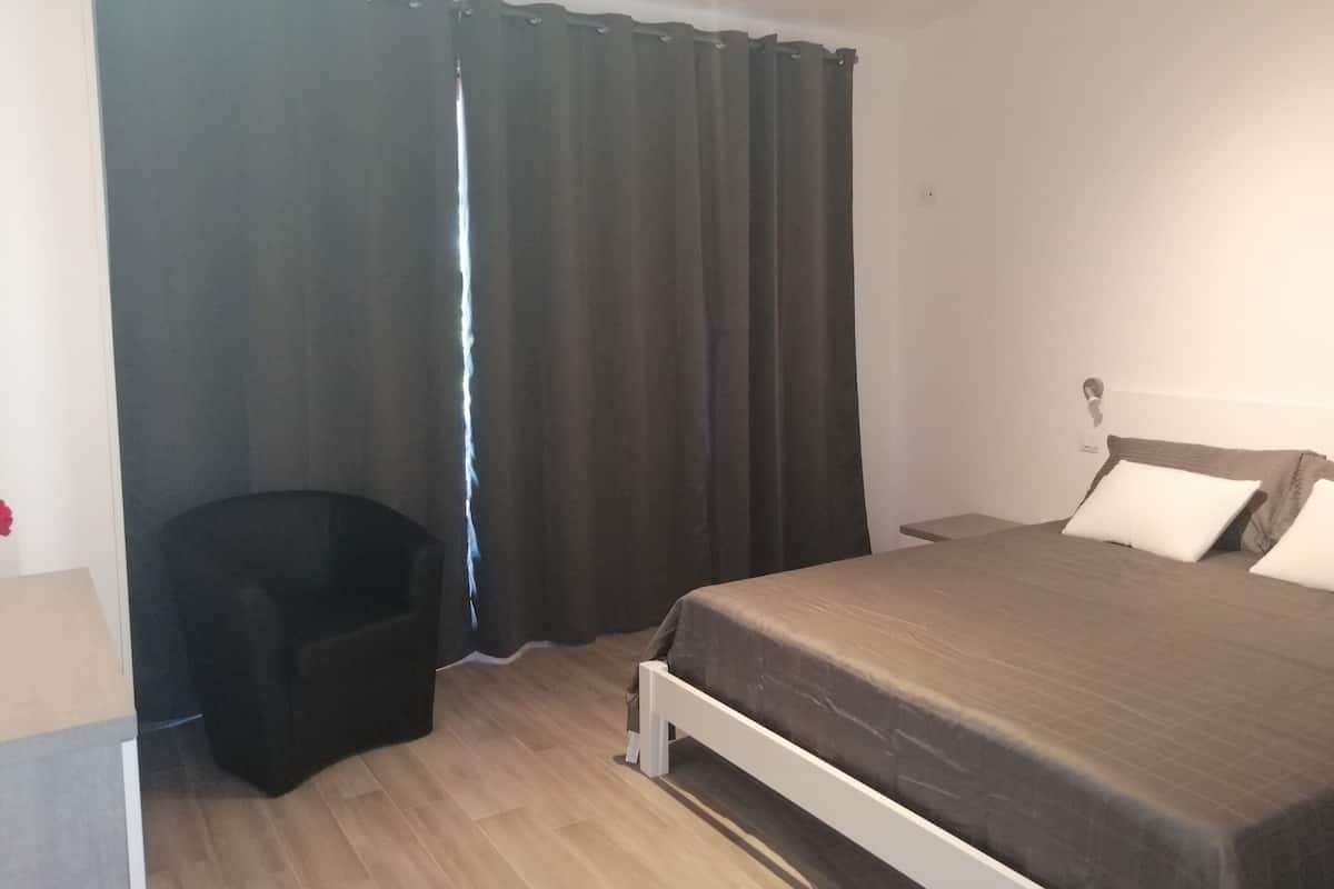 Une chambre à coucher avec un lit, une chaise et une fenêtre avec des rideaux.